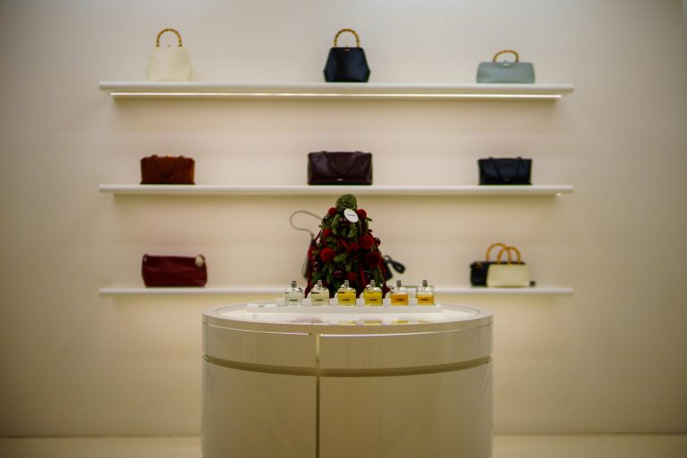 row of luxury handbags displayed on minimalists white shelving in a boutique setting