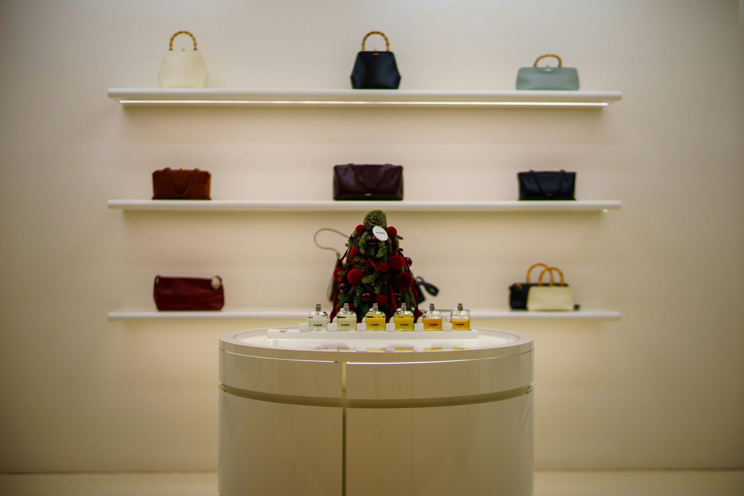 row of luxury handbags displayed on minimalists white shelving in a boutique setting
